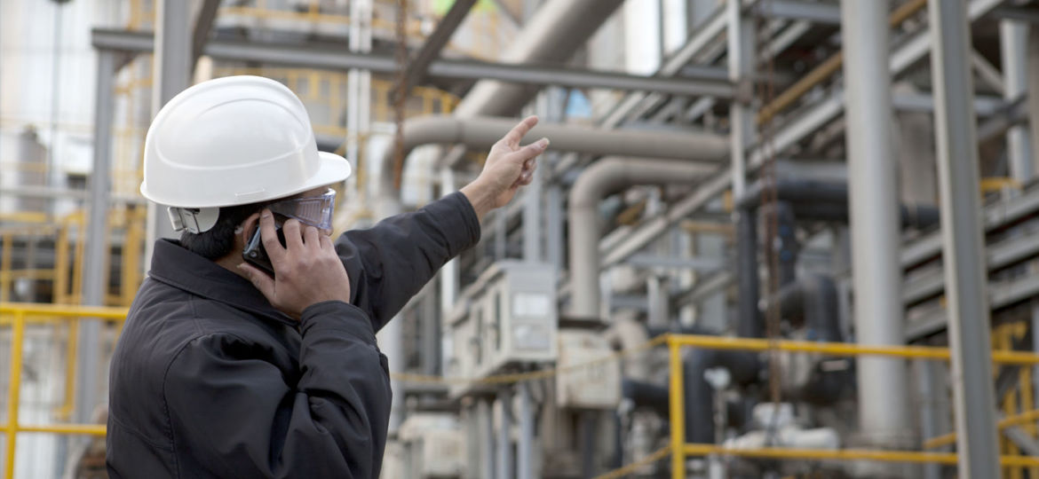 man in hardhat pointing up at pipelines