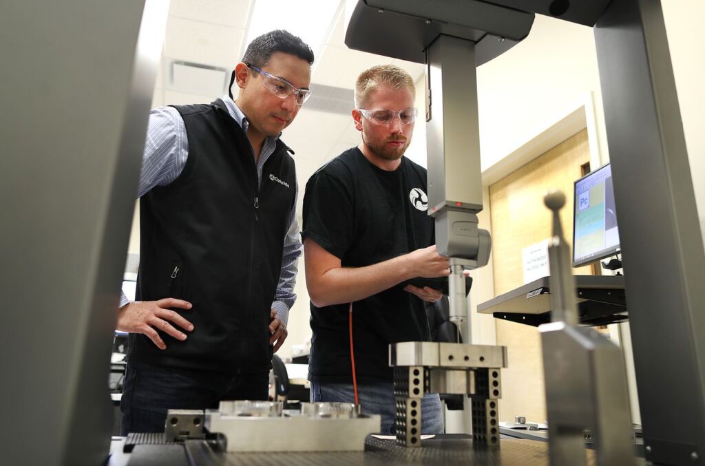 Hunter Carter, right, a quality engineer, used a computer-programmed probe that inspects the tolerances of a finished valve with Kyle Daniels, left.