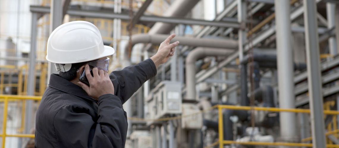 man in hardhat pointing up at pipelines